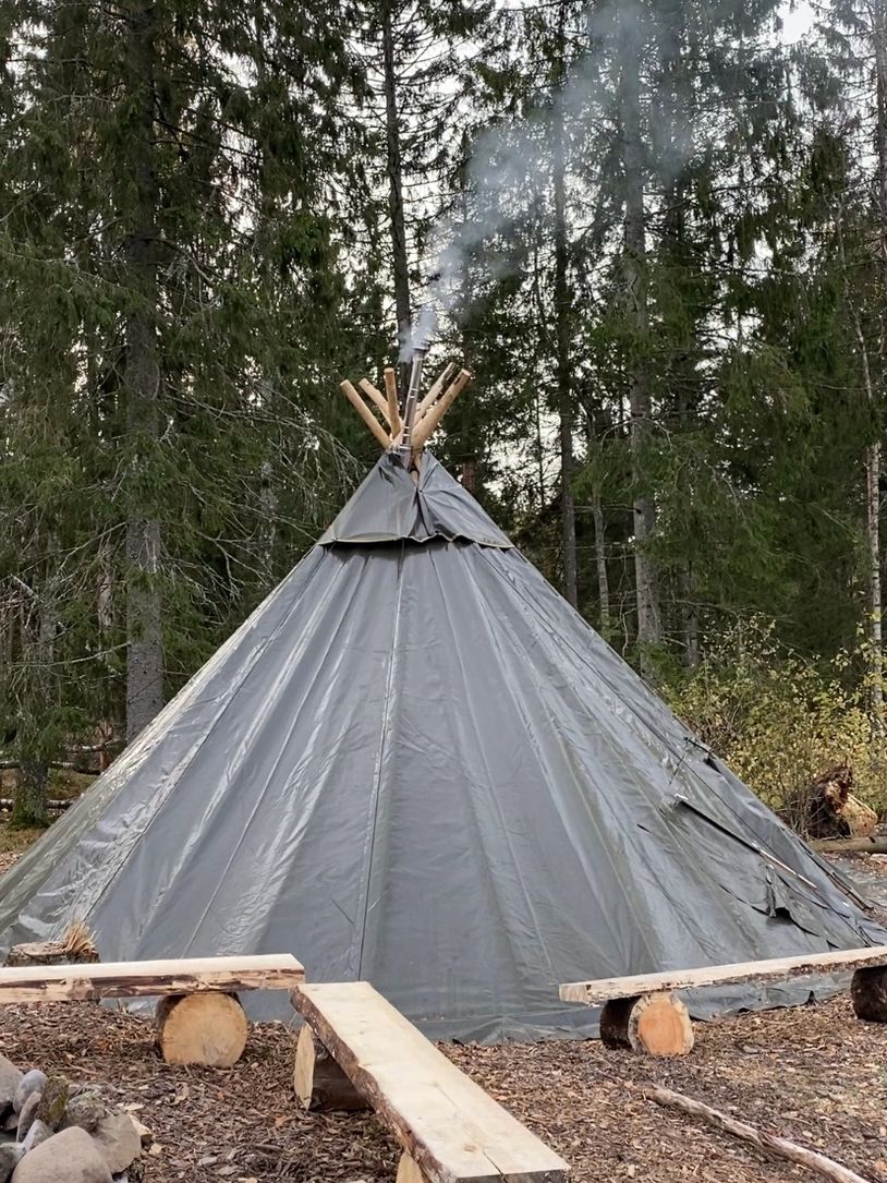 Telt i skogen med røyk som stiger opp.