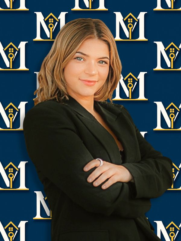 Confident woman in black blazer posing with arms crossed against a branded backdrop.