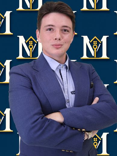 Young professional in a blue suit posing confidently with arms crossed.