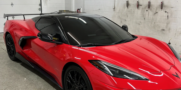 Red sports car with black accents parked indoors.
