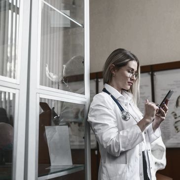 Female doctor with stethoscope using smartphone in medical office.