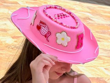 cute girl holding a cowgirl hat on her head