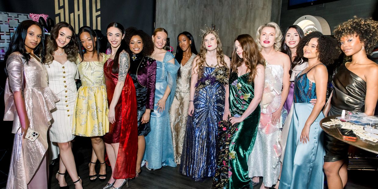Diverse group of women posing in elegant evening gowns at a glamorous event.