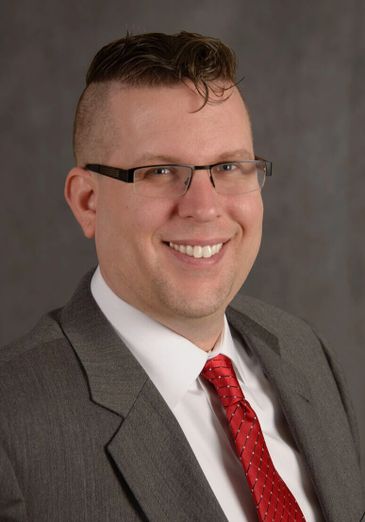 Man in a gray suit and red tie smiling.