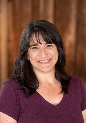 Smiling woman with dark hair wearing a maroon top.