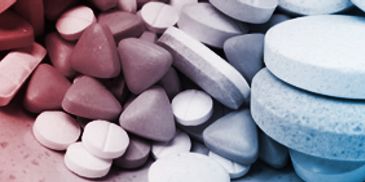 Various pills in different shapes and colors closely arranged.