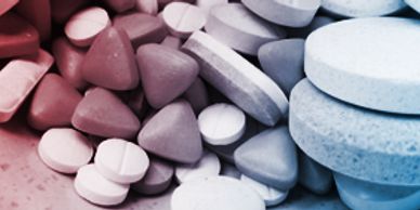 Close-up of various shaped and colored pills grouped together.