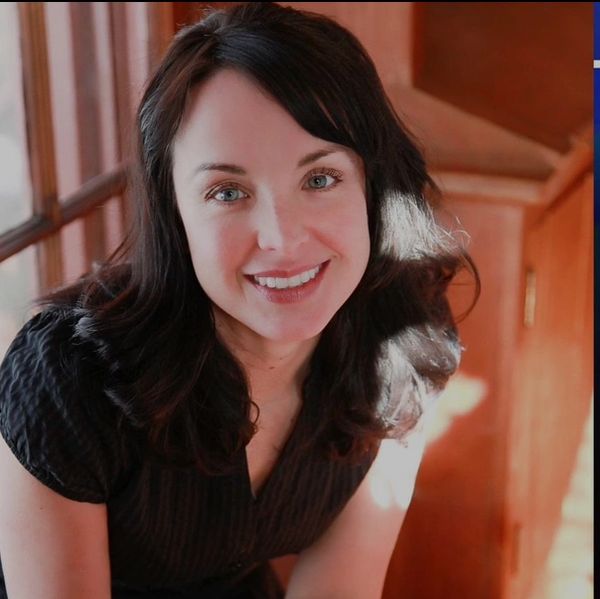 Smiling woman with dark hair in natural light.