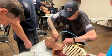Paramedics practicing cricothyroidotomy after failed intubation.
