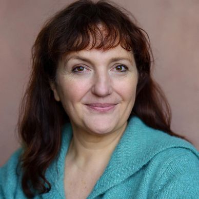 Smiling woman in teal sweater against a plain background.