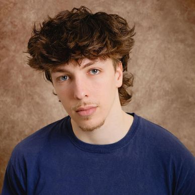 Young man with curly hair and blue shirt.