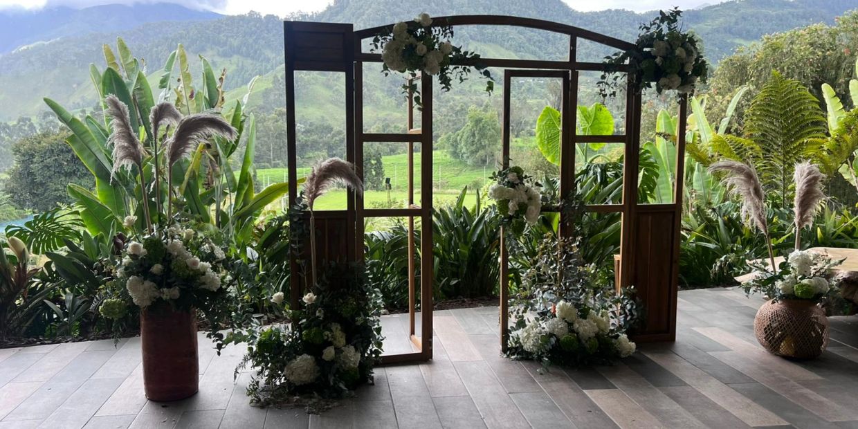 Floral arch setup with lush green mountain backdrop.