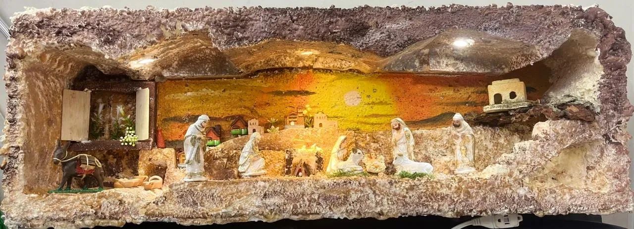 A nativity scene with figurines inside a rustic cave-like structure.