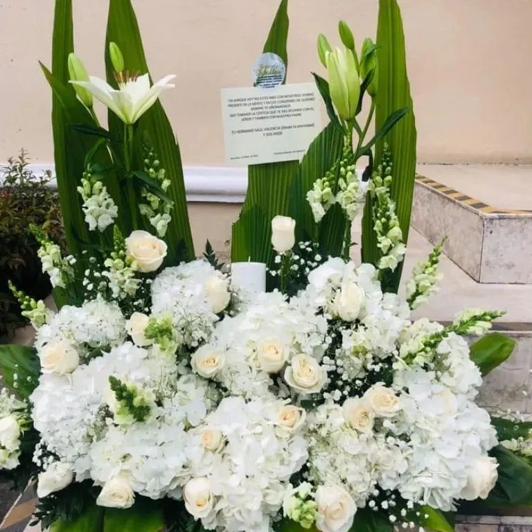 Elegant white floral arrangement with lilies, roses, and greenery.