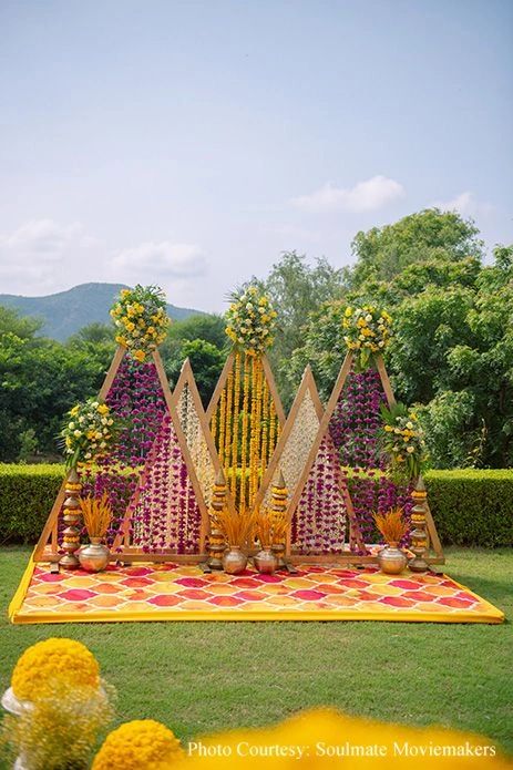 Colorful floral wedding mandap setup outdoors with vibrant decorations.