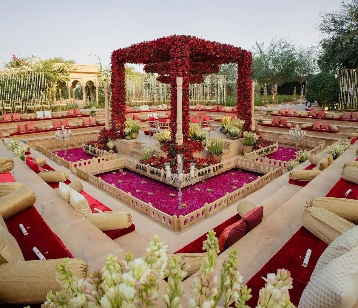 Luxurious outdoor seating area with red floral canopy and cushions.