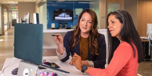 Two women collaborating at a computer in a modern office.