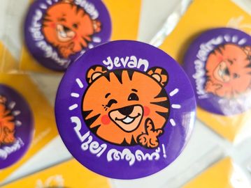 Purple button badge with a smiling tiger cartoon and text in Armenian.