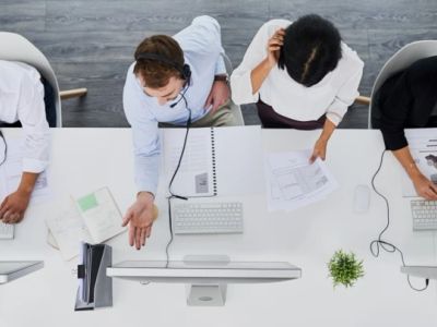 A team collaborating at a desk with computers and documents.