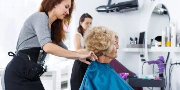 Hairdresser preparing to cut an elderly woman's hair.