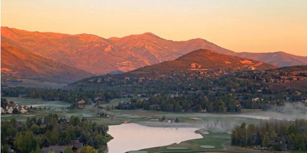 Sunset glow on mountains with a reflective lake below.