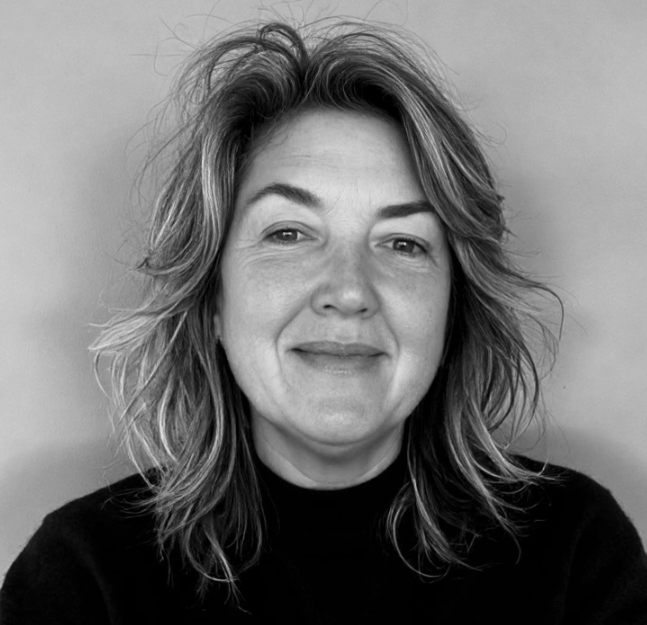Black and white portrait of a smiling woman with tousled hair.