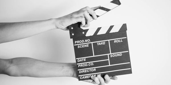 Hands holding a classic film clapperboard against a white background.