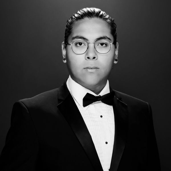 A formal black and white portrait of a man in a tuxedo.