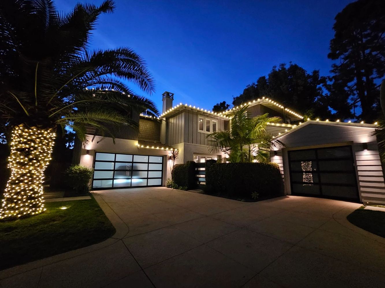 Modern house decorated with string lights at dusk.