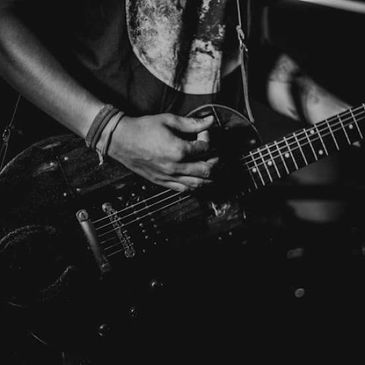 Close-up of hands playing an electric guitar in black and white.