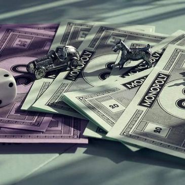 Monopoly game money and metal tokens on a table.