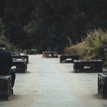 A person sitting alone on a bench in a quiet park pathway.