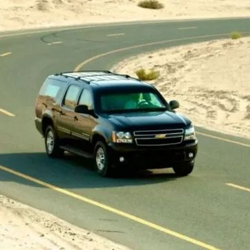 Black SUV driving on a curvy desert road.