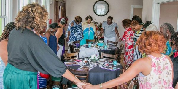 "Capricia Griffin holding hands with a group of women, engaged in prayer together, symbolizing unity and faith.