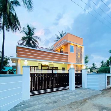 Modern two-story house with orange exterior and black gate at dusk.