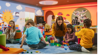 Children and a teacher playing with colorful blocks in a cheerful classroom.