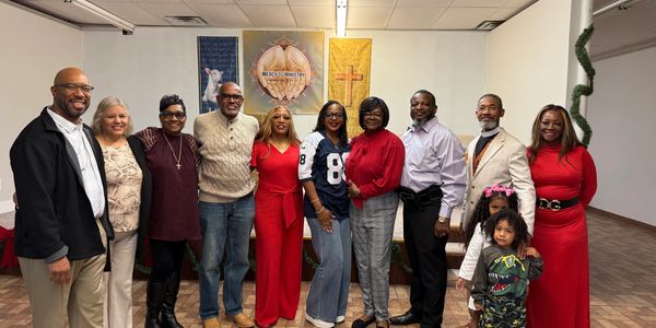 A group of people posing together indoors in front of ministry banners.