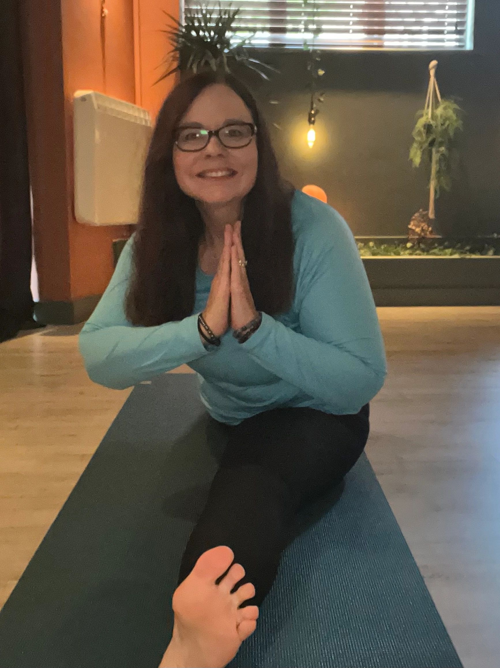 Angela doing full splits pose at the Yoga Den in Buxton. Smiling and looking happy.