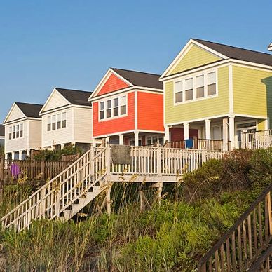 row of colorful homes on a grassy hill with stairs leading downward