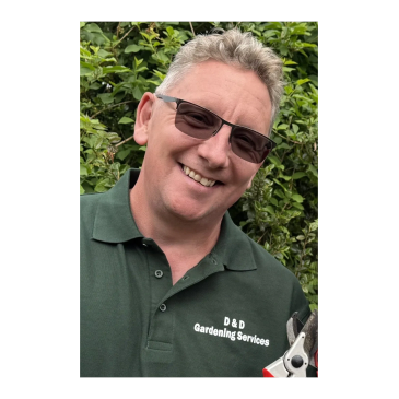 Man smiling wearing sunglasses and a gardening shirt.