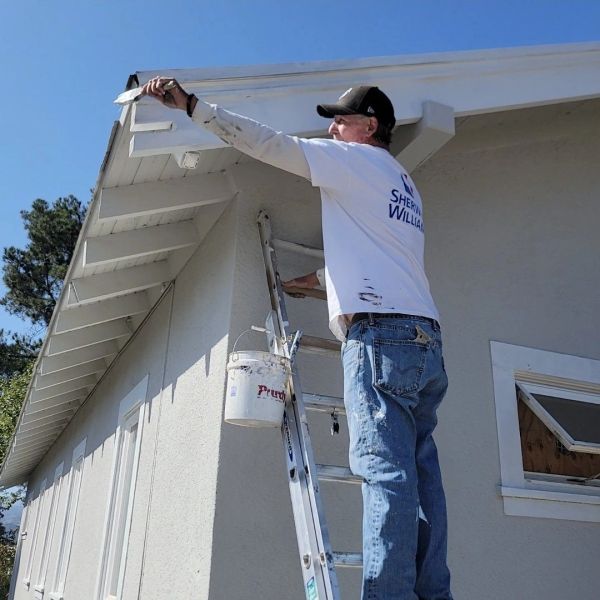 A&R Bentley Painting crew member caulking and painting eave trim on a San Jose home exterior