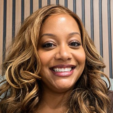 Smiling woman with wavy hair against striped background.