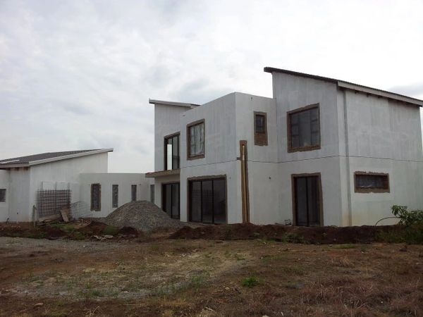 Modern house under construction with white walls and large windows.