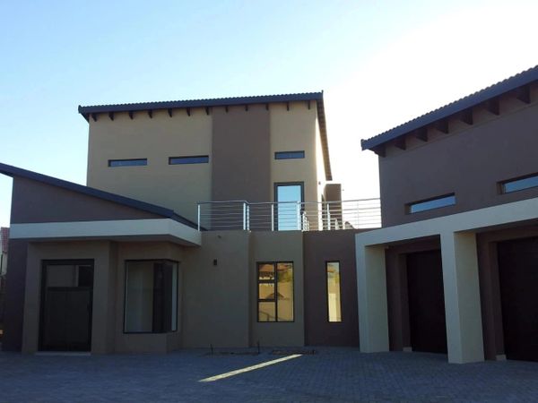Modern two-story house with a neutral color palette and large windows.