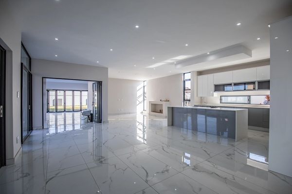 Spacious modern kitchen and living area with glossy marble floors and ample natural light.