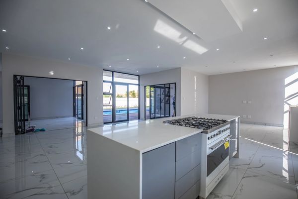 Modern kitchen with island and large windows overlooking a pool area.