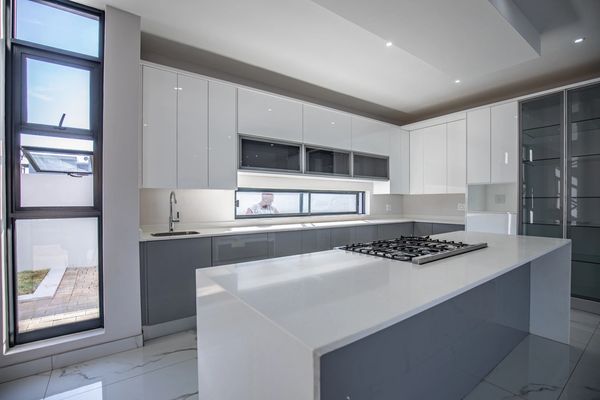 Modern kitchen with sleek white and gray cabinetry and a large island with a stovetop.