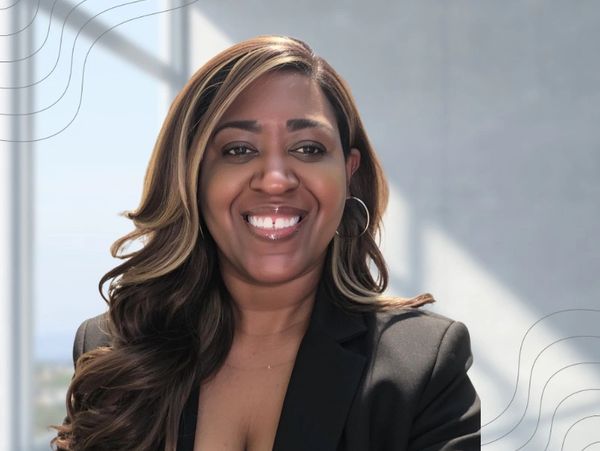 Smiling woman with highlighted hair in professional attire.