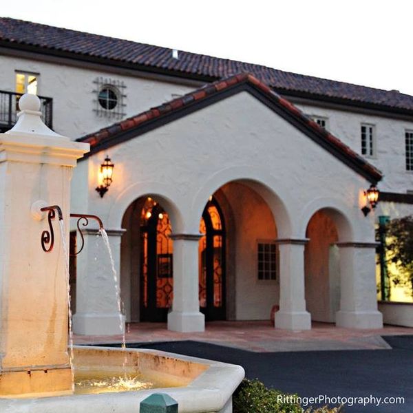 A Spanish-style building with arches and a fountain in front.