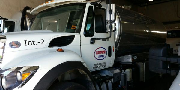 White tanker truck with company branding inside a garage.